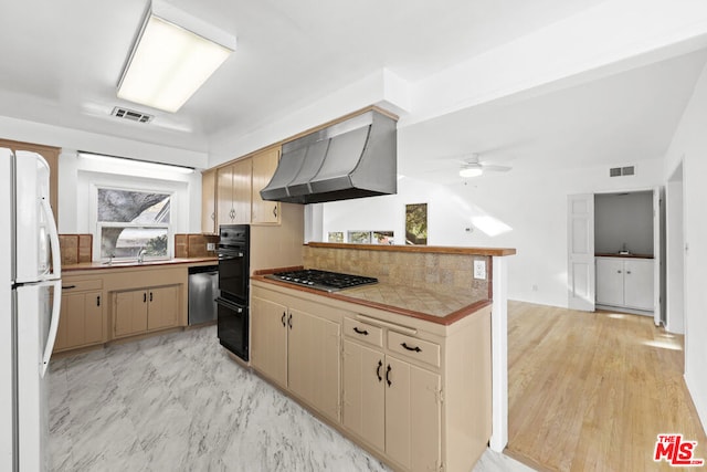 kitchen featuring ceiling fan, sink, range hood, backsplash, and appliances with stainless steel finishes