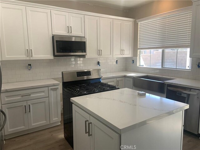 kitchen with stainless steel appliances, decorative backsplash, white cabinets, and sink