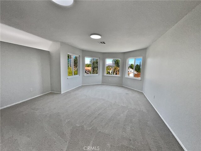 carpeted empty room with a textured ceiling