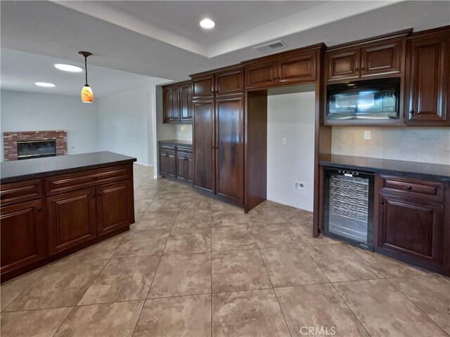 kitchen featuring a fireplace, decorative light fixtures, black microwave, wine cooler, and dark brown cabinets