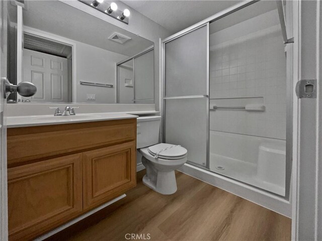 bathroom featuring an enclosed shower, wood-type flooring, vanity, and toilet