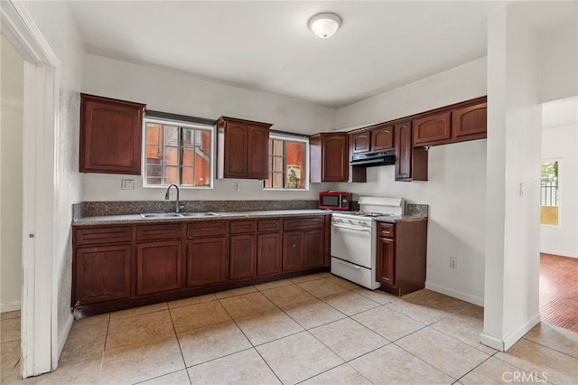 kitchen featuring white gas range, sink, and light tile patterned floors