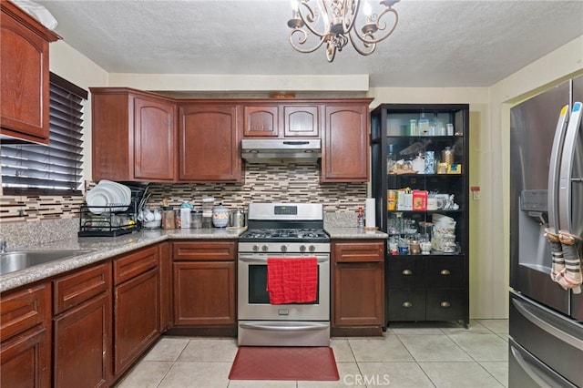 kitchen with a notable chandelier, decorative backsplash, stainless steel appliances, and light tile patterned flooring