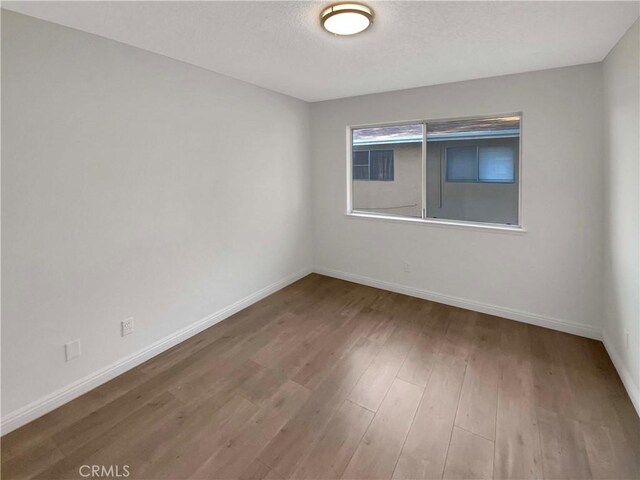 spare room featuring hardwood / wood-style flooring and a textured ceiling