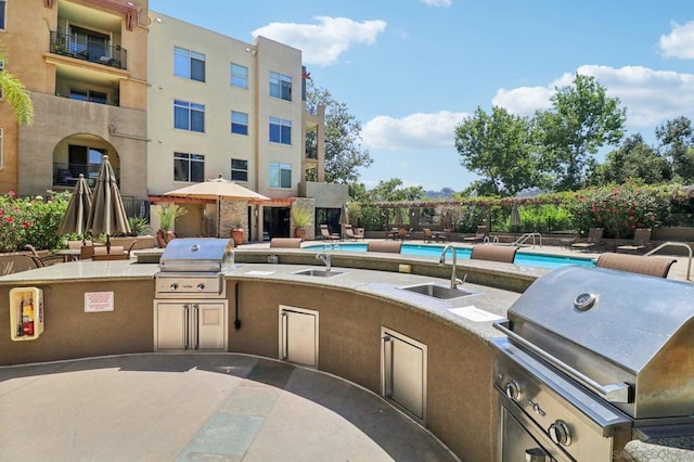 view of patio with an outdoor kitchen, sink, a community pool, and a grill