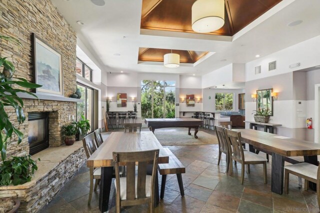 dining space featuring a healthy amount of sunlight, a fireplace, a tray ceiling, and billiards