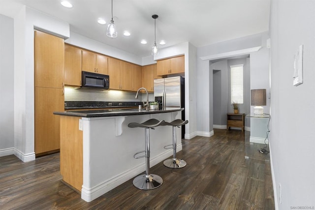 kitchen featuring dark hardwood / wood-style floors, pendant lighting, tasteful backsplash, and an island with sink