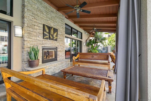 exterior space featuring lofted ceiling with beams, an outdoor stone fireplace, plenty of natural light, and wooden ceiling