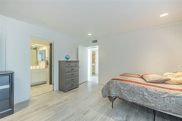 bedroom featuring connected bathroom and light hardwood / wood-style flooring