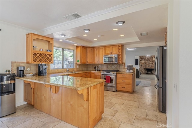 kitchen featuring kitchen peninsula, stainless steel appliances, a raised ceiling, a breakfast bar, and sink