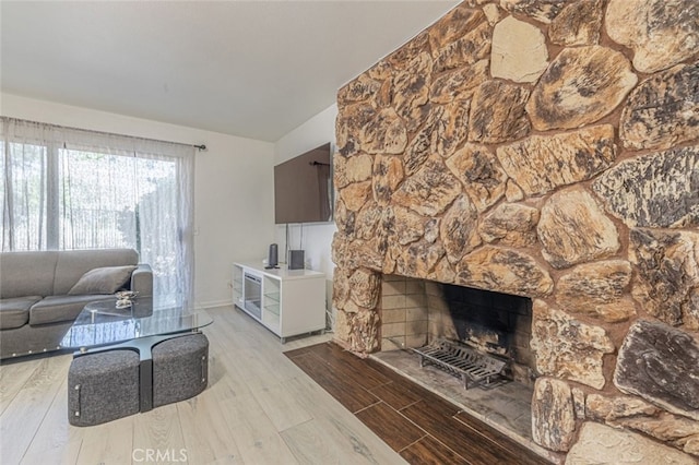 living room with hardwood / wood-style floors and a stone fireplace