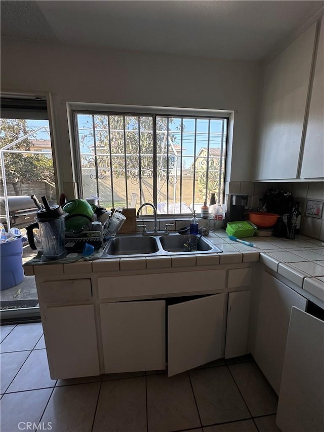 kitchen featuring sink, white cabinets, tile countertops, and light tile patterned flooring