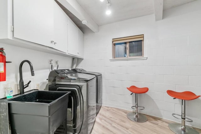 washroom featuring light hardwood / wood-style floors, cabinets, sink, and washing machine and dryer