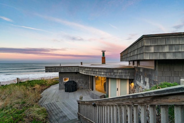 deck at dusk featuring a water view and grilling area