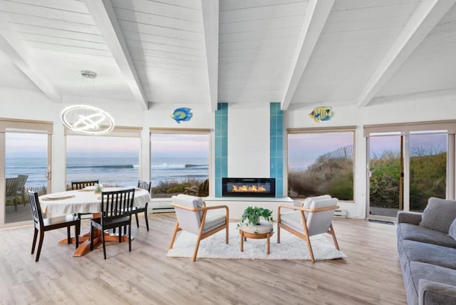 sunroom / solarium featuring a water view, a fireplace, beamed ceiling, and an inviting chandelier