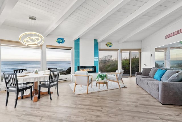 sunroom / solarium with a water view, beam ceiling, a tiled fireplace, and a notable chandelier