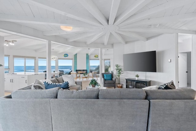 living room featuring a beach view, beamed ceiling, and a water view