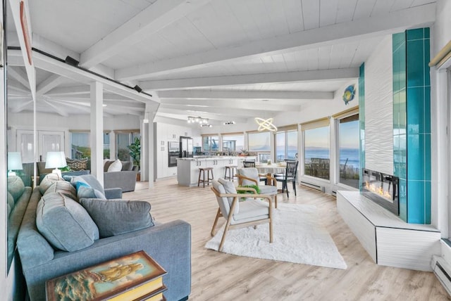 living room featuring a water view, lofted ceiling with beams, a baseboard radiator, and light hardwood / wood-style floors