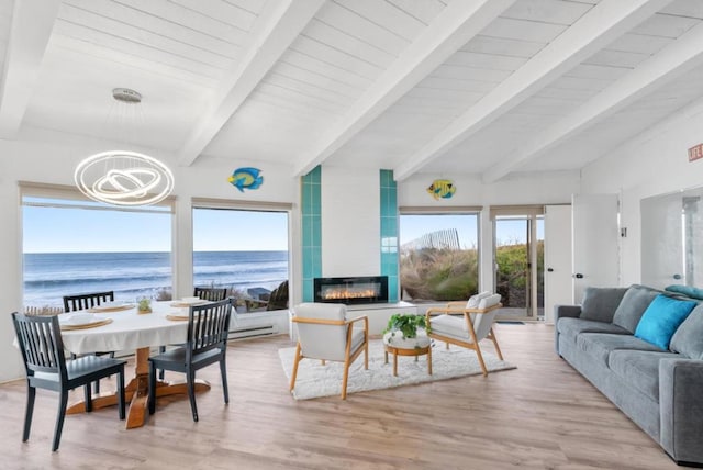 interior space featuring light hardwood / wood-style floors, a chandelier, a water view, a tile fireplace, and beam ceiling