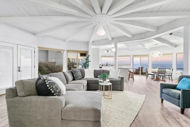 living room with a water view, vaulted ceiling with beams, french doors, and light hardwood / wood-style floors