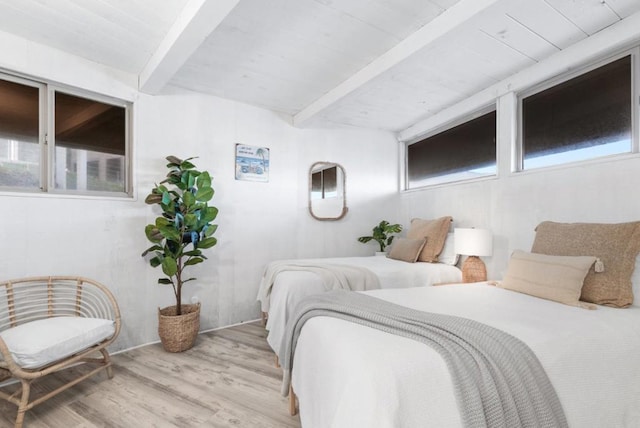 bedroom featuring light wood-type flooring, multiple windows, and beamed ceiling