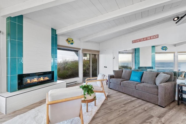 living room featuring light wood-type flooring, beamed ceiling, and a fireplace