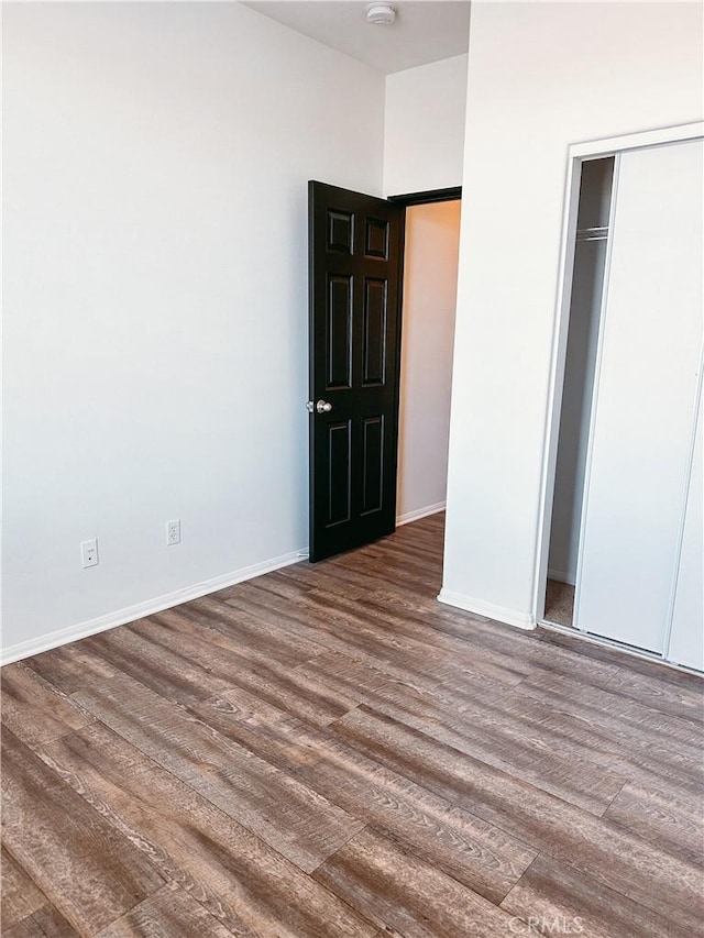 unfurnished bedroom featuring dark wood-type flooring and a closet