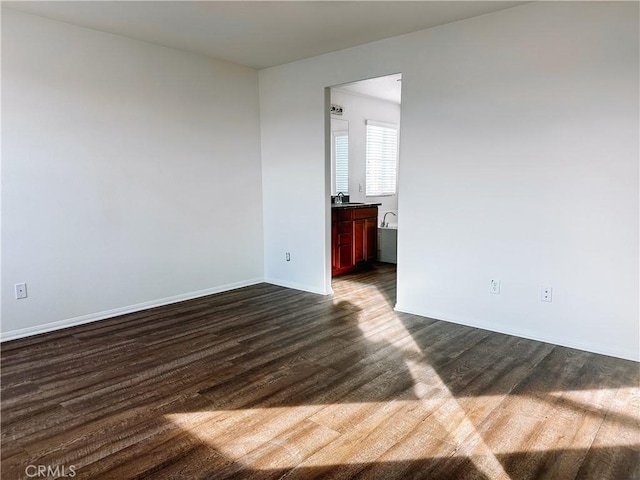 spare room with dark wood-type flooring and sink