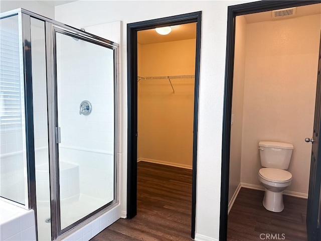 bathroom with toilet, wood-type flooring, and an enclosed shower