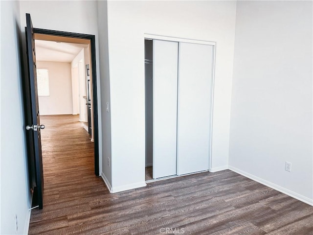 unfurnished bedroom with a closet and dark hardwood / wood-style flooring