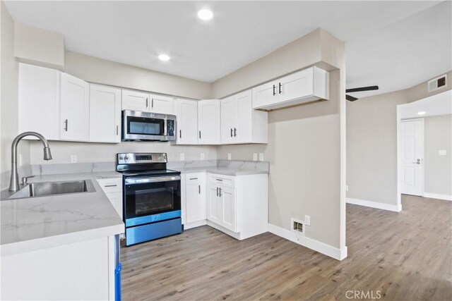 kitchen featuring ceiling fan, sink, appliances with stainless steel finishes, white cabinets, and light stone counters