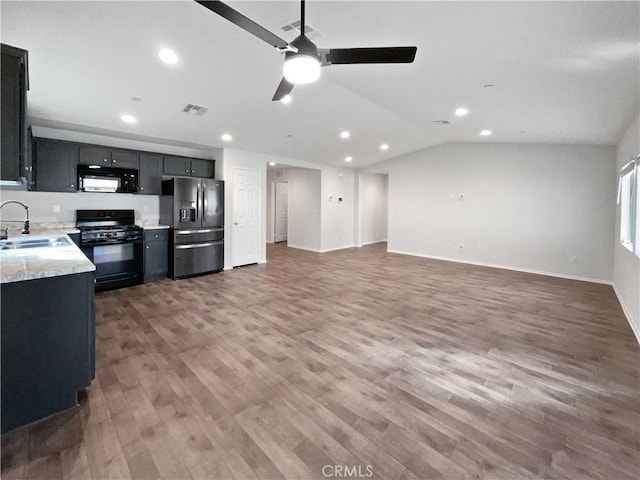 kitchen with light stone counters, visible vents, open floor plan, a sink, and black appliances