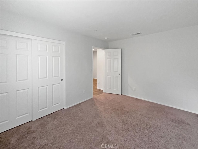 unfurnished bedroom featuring carpet floors, a closet, visible vents, and baseboards