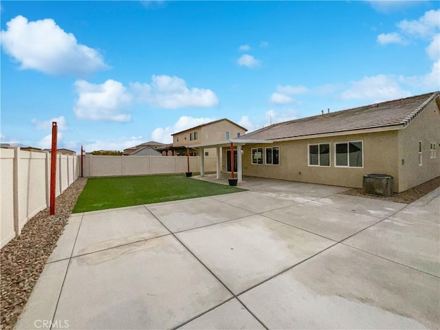 rear view of property with stucco siding, a fenced backyard, a yard, and a patio