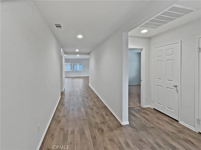 hallway with visible vents, baseboards, and wood finished floors