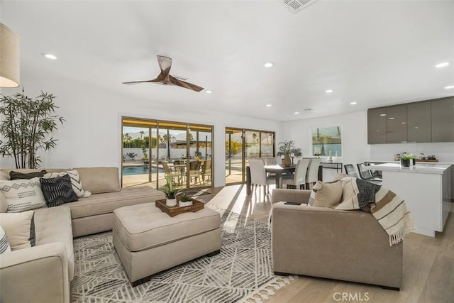 living room with ceiling fan and light hardwood / wood-style flooring