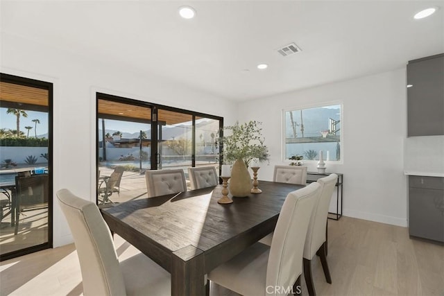 dining space featuring light wood-type flooring, a wealth of natural light, and a water view