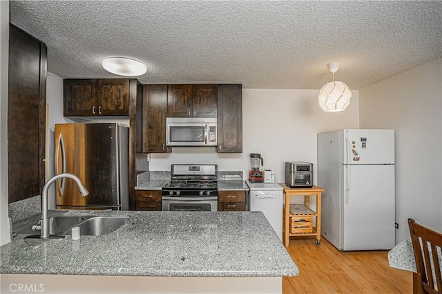 kitchen with light stone countertops, sink, a textured ceiling, and stainless steel appliances