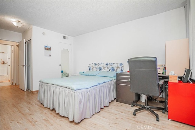 bedroom with a textured ceiling and light hardwood / wood-style flooring