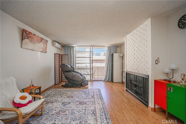 living area featuring a fireplace, wood-type flooring, a wall mounted air conditioner, expansive windows, and a textured ceiling