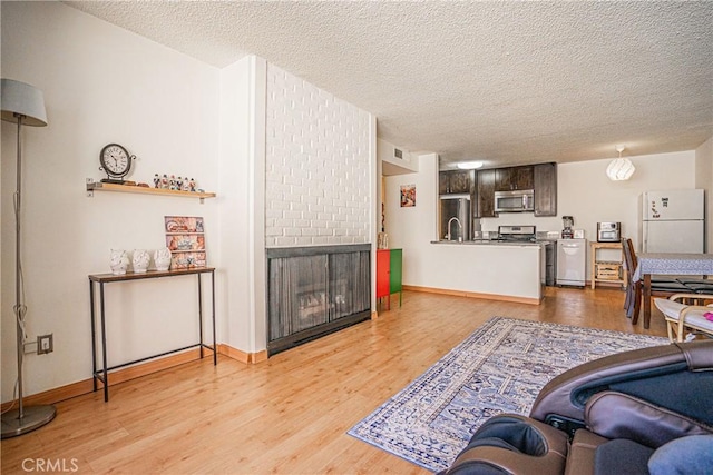 living room with a textured ceiling, a fireplace, and light hardwood / wood-style floors