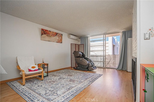 sitting room with floor to ceiling windows, a textured ceiling, an AC wall unit, and hardwood / wood-style floors