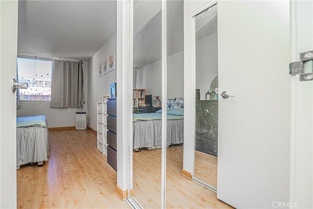 corridor with a textured ceiling and hardwood / wood-style flooring