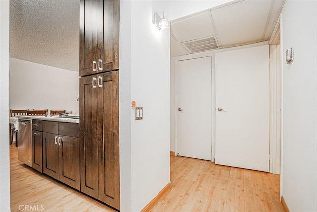 corridor with a textured ceiling and light hardwood / wood-style floors