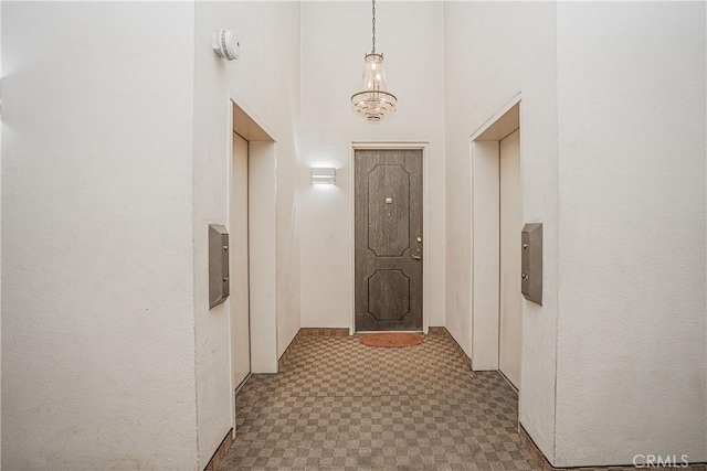 hall with a chandelier, a towering ceiling, and elevator