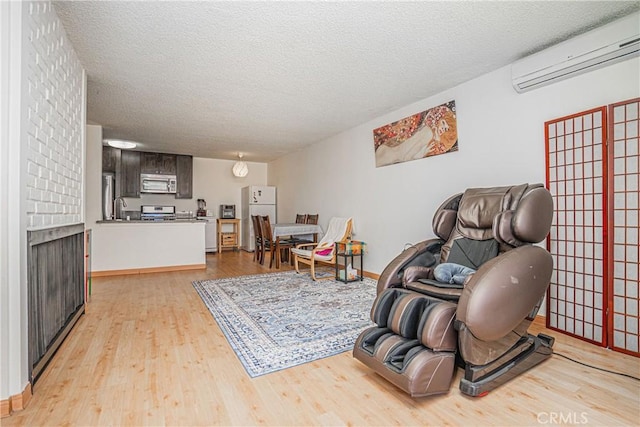 living area featuring light wood-type flooring, a wall mounted AC, sink, and a textured ceiling