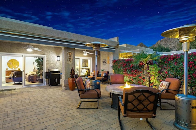 patio at twilight with ceiling fan and a fire pit