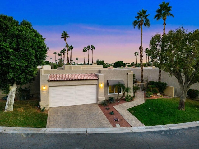 adobe home featuring a garage and a lawn