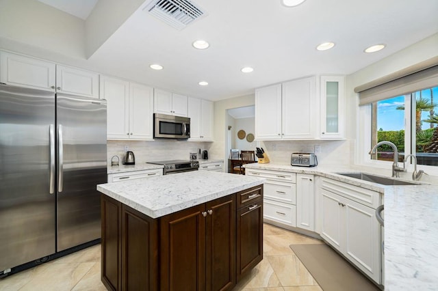 kitchen with stainless steel appliances, decorative backsplash, a kitchen island, and sink