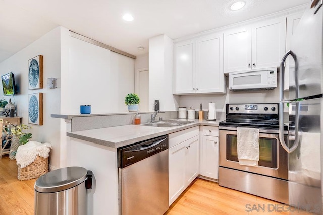 kitchen with light wood-type flooring, appliances with stainless steel finishes, white cabinets, and sink